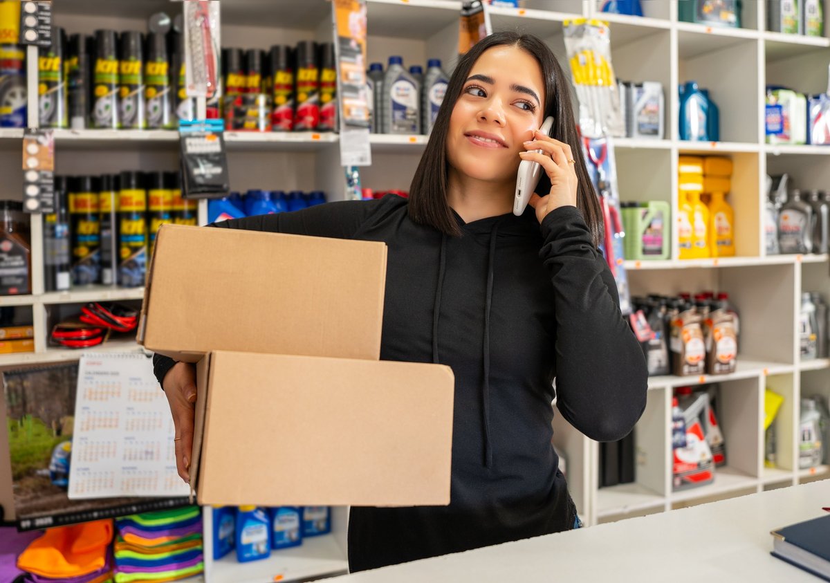 Woman holding boxes and talking on mobile phone in a retail store